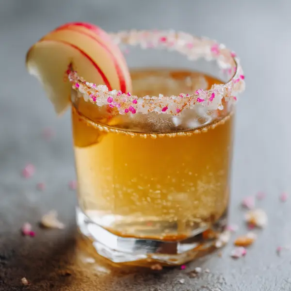 Apple cider vinegar and pink salt detox drink with apple slice and salt rim